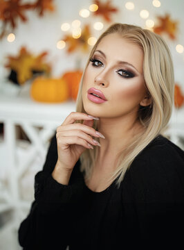 Portrait einer sch&ouml;nen blonden Frau mit perfektem Permanent Make-Up und Gel-Fingern&auml;geln mit herbstlicher Deko