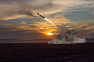 Obraz premium launching a missile from an air defence system against the background of an evening field and the setting sun.