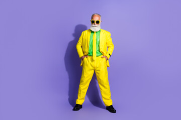 Full body portrait of funny extravagant aged man posing yellow suit isolated on purple color background