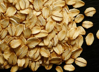 Oatmeal, a sprinkling of flour on a black background. Oats or flax seeds, whole grain and healthy food concept.