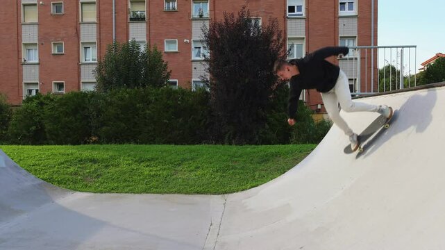 Skater Practicing Tricks on the Half-Pipe at Sunset in the Skate park