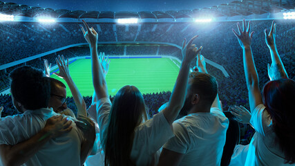 Fans in white shirts celebrate and pointing fingers toward soccer field, with field brightly illuminated and stadium packed with spectators. Concept of sport event, championship, celebration, victory © Lustre Art Group 