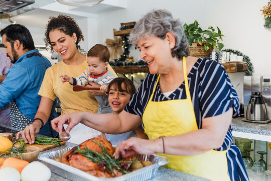 Latin family cooking together for Christmas dinner at home in Mexico Latin America, hispanic mother, grandparents and daughter preparing turkey meat in holidays