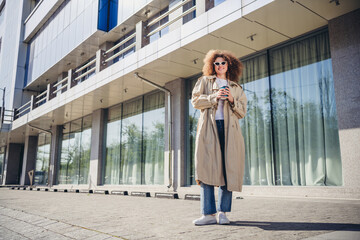 Photo of good mood cute girl dressed stylish beige clothes walking big city center spring sunny weather outdoors