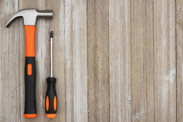 Retro orange screwdriver and hammer on wood background