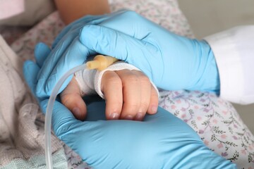 Doctor and child with intravenous drip at hospital, closeup