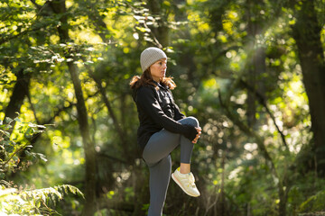 sporty woman doing a leg stretch warm up exercise outdoors in the park, autumn, fall fitness concept