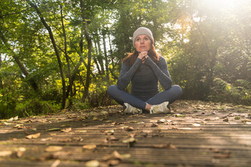 Sporty woman sitting on a boardwalk resting after exercise outdoors, autumn, fall fitness concept