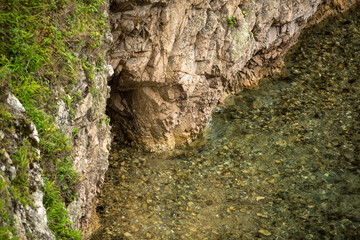 There is a towering rocky cliff situated right next to a body of water