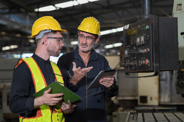 Two male engineer checking, repair, maintenance CNC machine in factory. Group of male technician working with CNC machine during manufacturing process