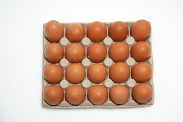 A dozen eggs are sitting in a carton. The eggs are brown and appear to be fresh