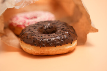A chocolate donut sits in a paper bag. The bag is brown and the donut is brown and white