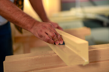 Close up view of man working on a piece of furniture in a carpenters shop.