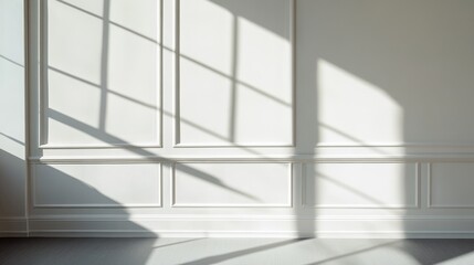 Obraz premium Gentle light filters through a window, casting soft shadows on a blank wall. The subtle play of light and shadow creates a tranquil atmosphere, perfect for relaxation