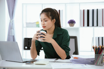 Confident Asian businesswoman in her office checking financial reports on her laptop. Analyzing data, planning strategies and full of success, professionalism and entrepreneurial spirit.