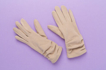 Beige gloves on color background, top view