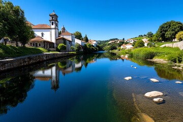 Obraz premium River Alcoa flowing peacefully through AlcobaÃ§a, reflecting the surrounding greenery and historical buildings