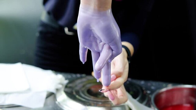 Slow motion footage of an animator dipping a child's hand in purple paraffin