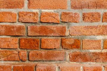 Fototapeta premium A textured wall composed of weathered red bricks reveals a rich palette of earthy tones and age-old character.