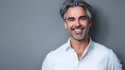 Obraz premium Senior Man With Bright Smile And Gray Hair Wearing Casual White Shirt Against Gray Wall