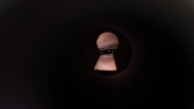 Person looking through keyhole observing with suspicious eye