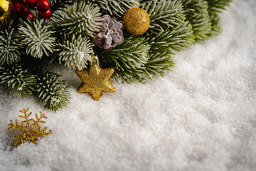 Christmas Holiday background with snow, fir tree and decorations with christmas light behind. Christmas golden balls on a winter festive background.