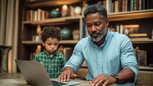 Grandfather helping young boy with homework on laptop at home