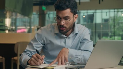 Indian man male Arabian guy businessman freelancer manager business entrepreneur work online in cafe restaurant write paperwork notes count bills writing notebook confused shock debt credit payment - Powered by Adobe