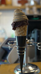 Delicious ice cream cone with creamy chocolate and vanilla swirl, showcased in a modern holder inside a cozy café, evoking a sense of indulgence and sweet delight