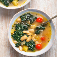 Black cabbage (Toscan kale or cavolo nero) Minestrone soup with white Cannellini beans on the white background. Italian Tuscan Medici winter recipes. Healthy tradition vegetarian food, top view
