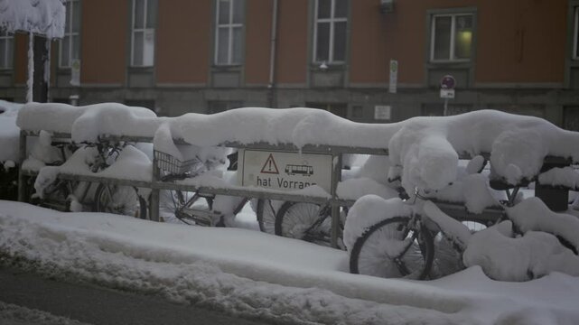 Munich, Germany. Snowfall in Muenchen. Snow covered bicycles in city parking lot. Snow drifts and bikes in snow in a parking area. Schneeeinbruch in Munchen, Deutschland. 