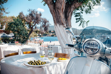 An ideal Greek setup by the sea in Neos Marmaras, parked scooter in the shadow of the tree, little table with Greek cuisine overlooking the port