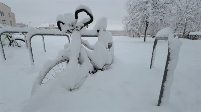 Munich, Germany. Snowfall in Muenchen. Snow covered bicycles in city parking lot. Snow drifts and bikes in snow in a parking area. Schneeeinbruch in Munchen, Deutschland. 