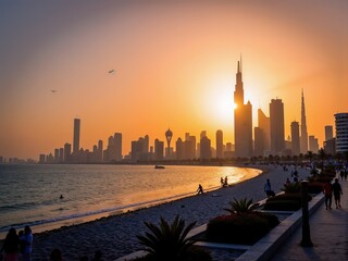 Obraz premium A stunning sunset casts a warm glow over a beach with people strolling along the shore, while a distant, impressive city skyline stretches high into the colorful sky.