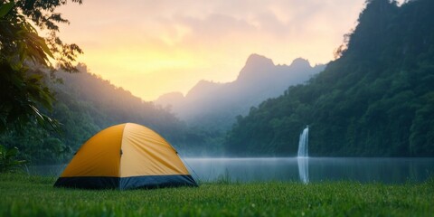 tent on grass field near lake and waterfall background