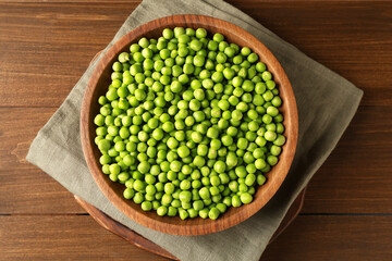 Fresh green peas in bowl on wooden table, top view