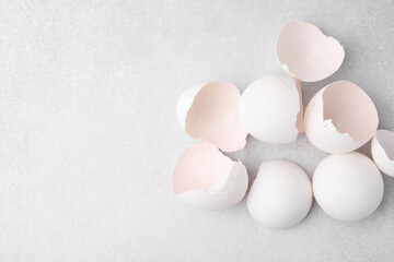 Broken eggshells on grey textured table, top view. Space for text