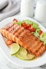 Delicious grilled salmon fillet with vegetable salad and lime on white marble table, closeup