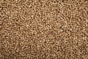 Wood pellet cat litter as background, top view