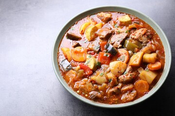 Delicious stew with vegetables in bowl on grey table, closeup