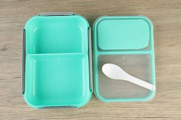 Empty plastic lunch box with cutlery on wooden table, top view