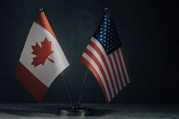 Table flag of United States America and Canada on dark background. Cooperation between two...
