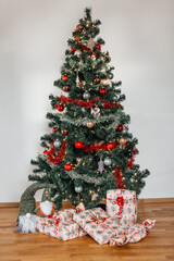 Christmas tree with presents under it on the wooden floor and white wall background