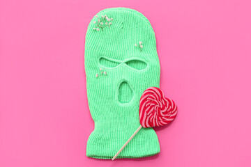 Balaclava with lollipop and flowers on pink background