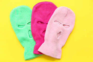 Set of stylish balaclavas on yellow background
