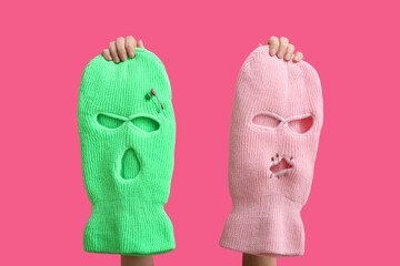 Female hands with balaclavas on pink background, closeup