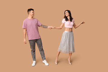 Happy young couple dancing on brown background