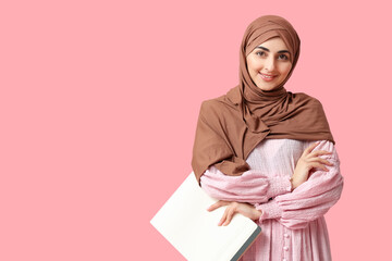 Beautiful Muslim woman with clipboard on pink background