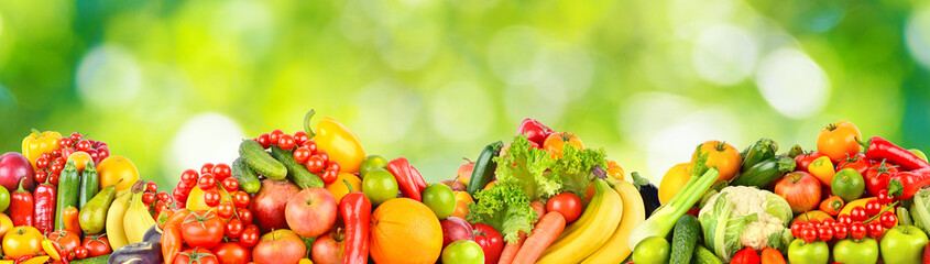 Panorama multicolored fresh fruits and vegetables on green background.