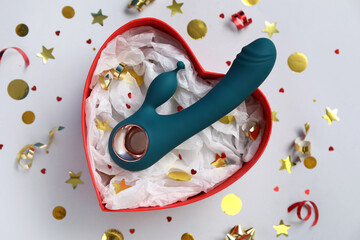 Composition with gift box, vibrator and confetti on grey background